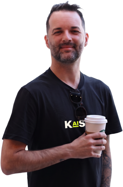 Drew Kaiser holding a coffee, wearing a KAISER shirt